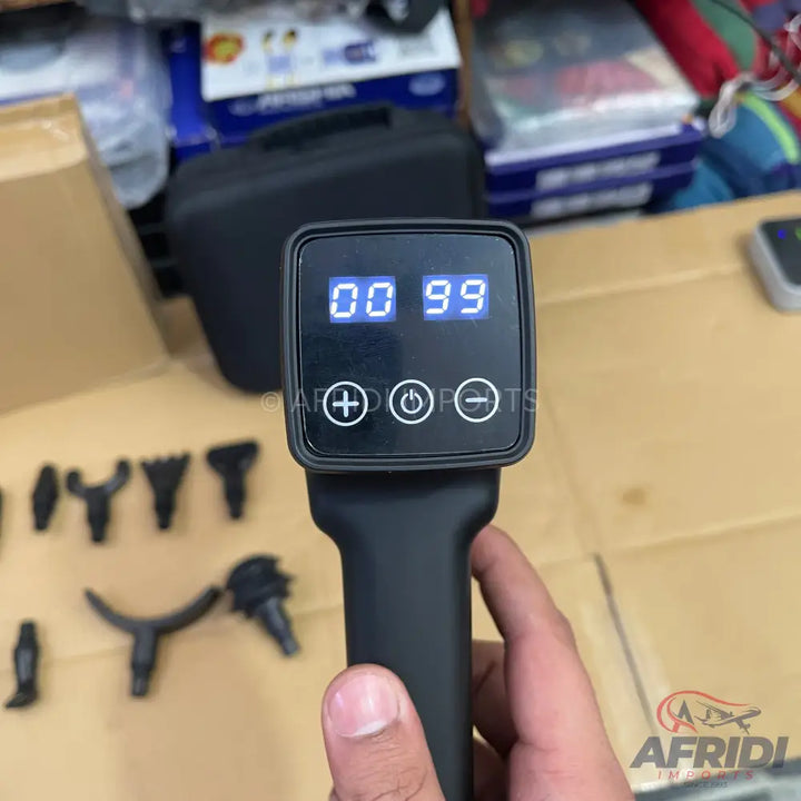 Black handheld massage gun with a digital display and multiple interchangeable head attachments.