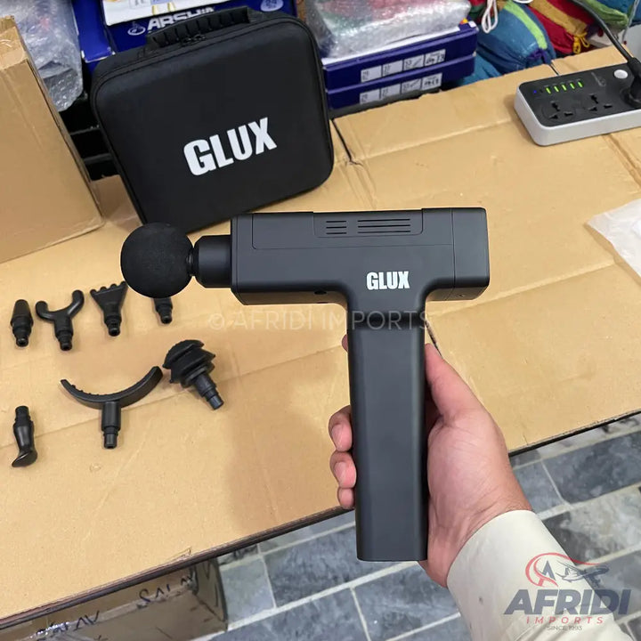 Black handheld percussive massage gun with multiple interchangeable head attachments and a carrying case.