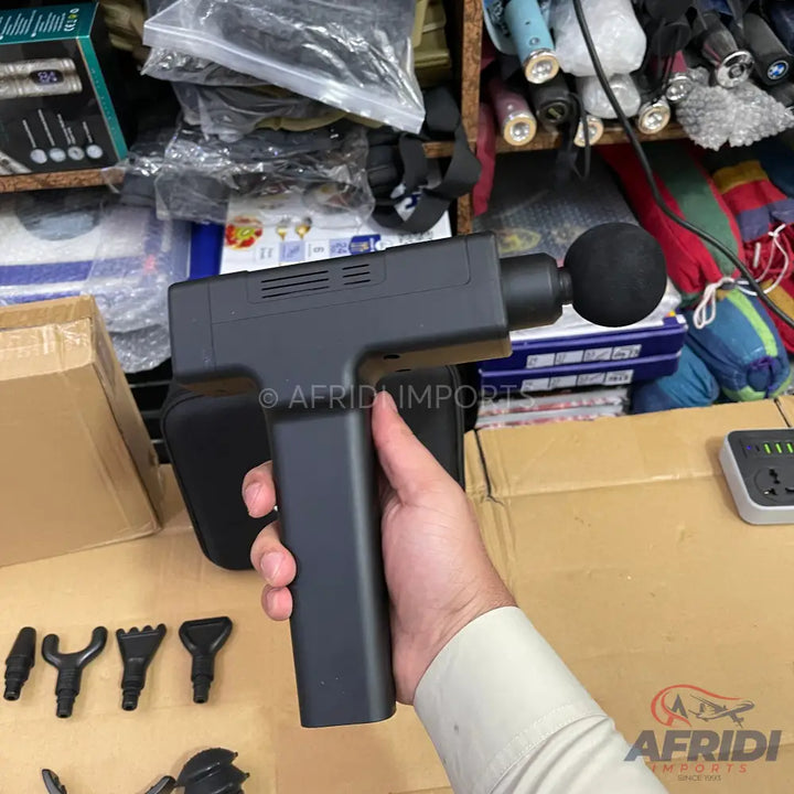 A black, handheld percussion massage gun with multiple interchangeable heads.