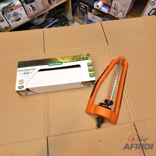 An orange oscillating sprinkler with a white box.