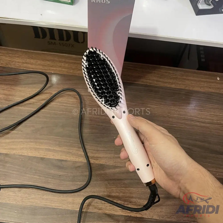 A light pink electric hair straightening brush with black bristles and a black power cord.