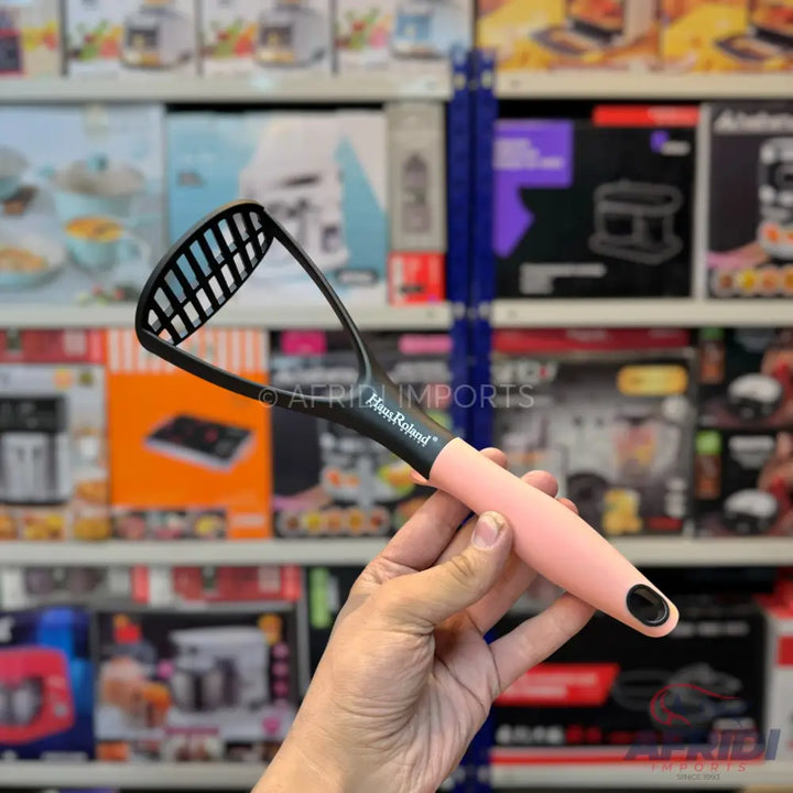 Black and pink potato masher with a slotted head.