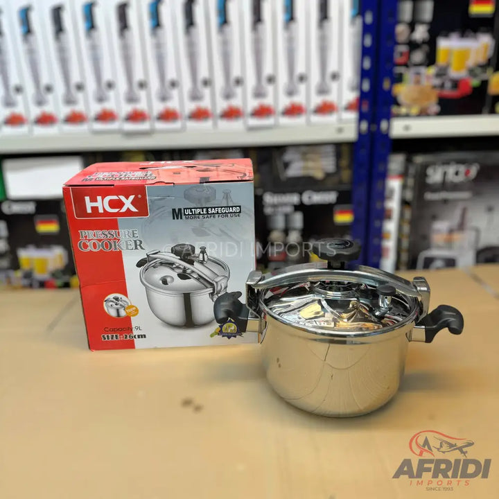 A stainless steel pressure cooker with a black handle and a matching box.