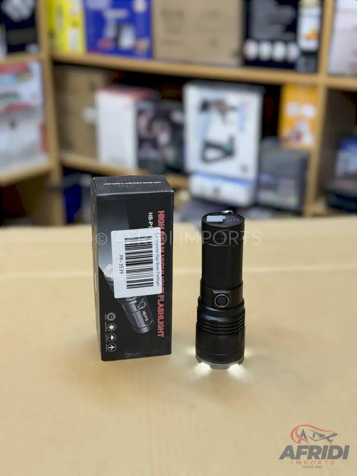 A black, high-power LED flashlight with an illuminated base, packaged in its box.