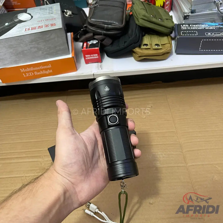 Black, handheld LED flashlight with a side button and wrist strap.