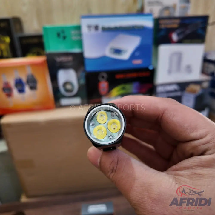 A handheld black flashlight with three bright yellow LED bulbs.