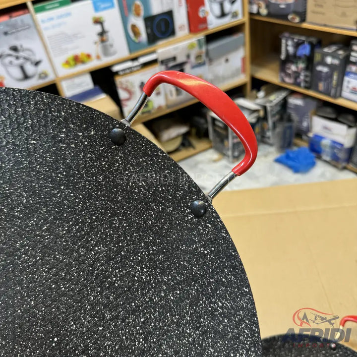 Black non-stick griddle with red handles.