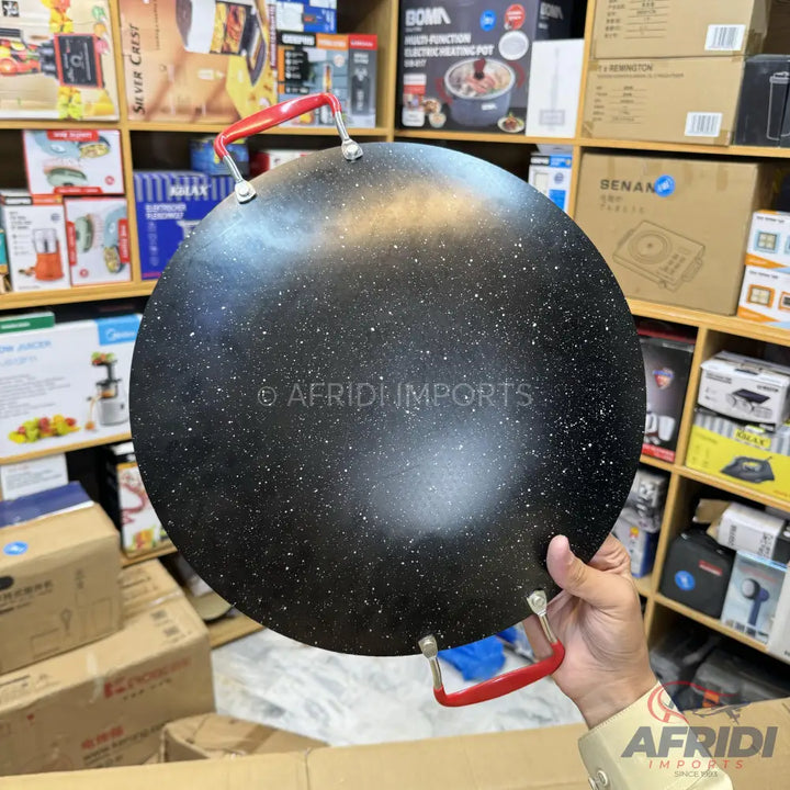 Black non-stick flat frying pan with red handles.
