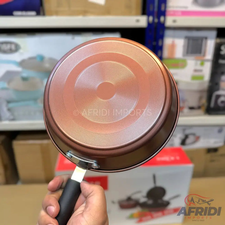 Copper-colored non-stick frying pan with a black handle.