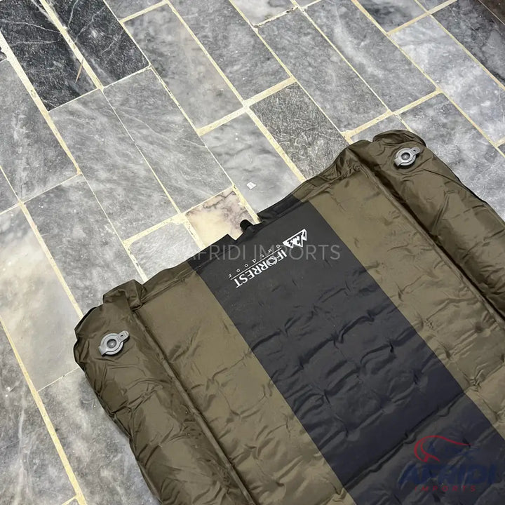 An olive green and black striped self-inflating sleeping pad with two air valves.