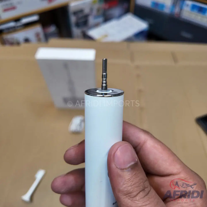 White electric toothbrush handle with a metallic silver top and a protruding metal rod.