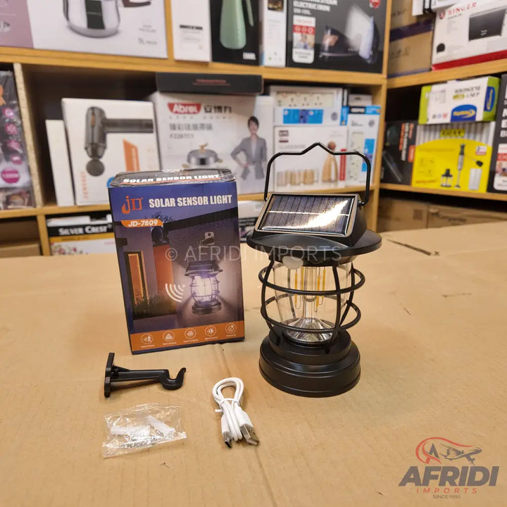 A black solar-powered lantern with a built-in solar panel and a cage-like design.