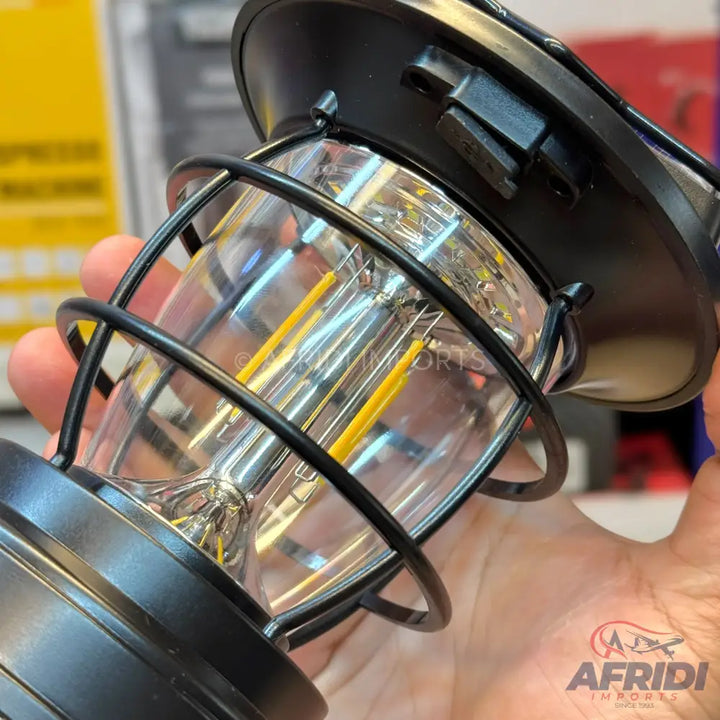 A black metal-caged LED lantern with a clear glass body.