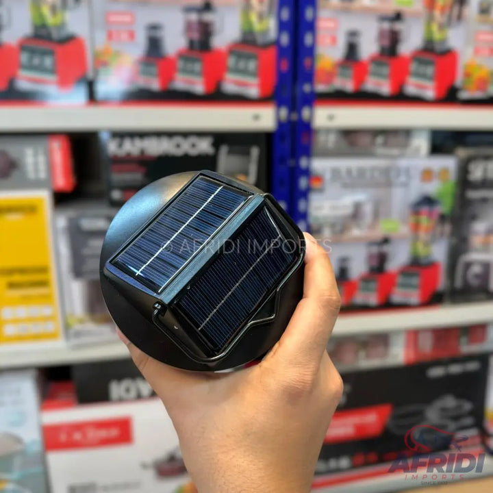 A dark-colored, circular solar-powered light with a rectangular solar panel on top.