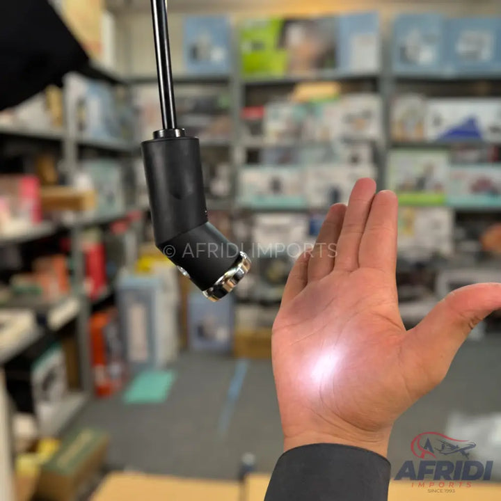 A black, flexible-necked flashlight with a reflective tip shining a bright light onto a person’s open palm.