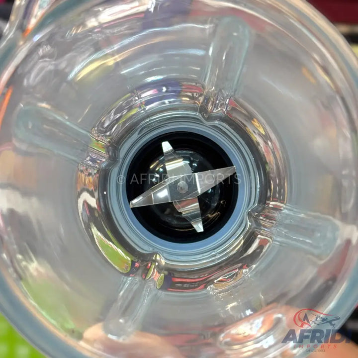 A clear glass blender jar with a four-pronged metal blade assembly at the bottom.