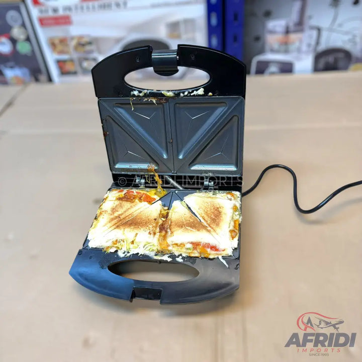 An open, used black sandwich maker with two toasted sandwiches inside.