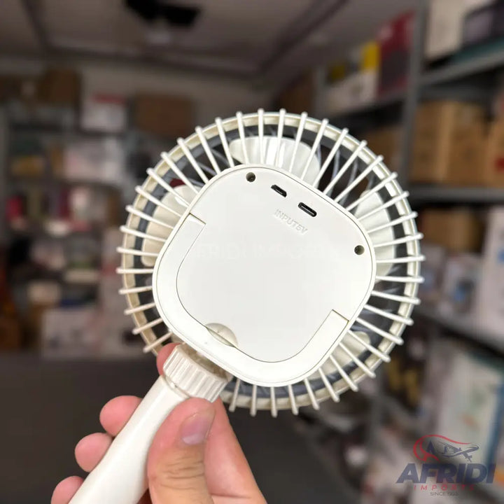 White portable handheld fan with a battery compartment and two charging ports.