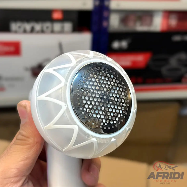 A handheld white fabric shaver with a circular metal mesh head.