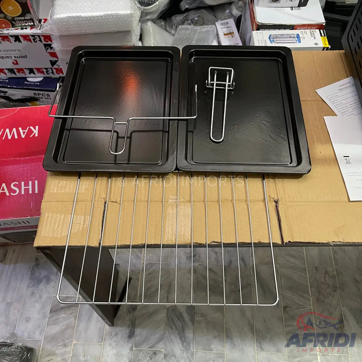 Two rectangular black baking trays with metal handles and a metal rack.
