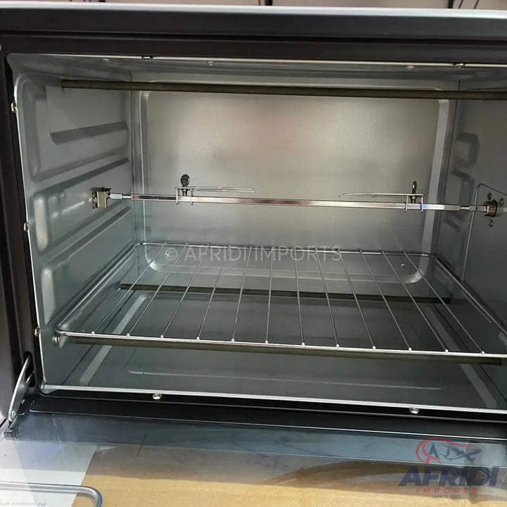 Empty, stainless steel interior of a new electric oven with a rotisserie spit and rack.