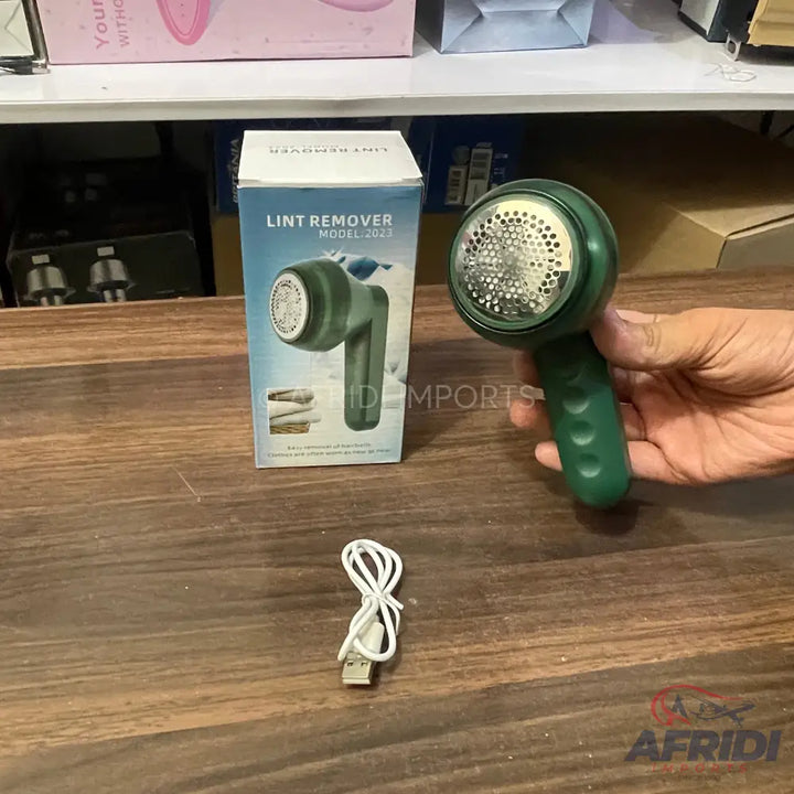 A green handheld lint remover with a USB charging cable.