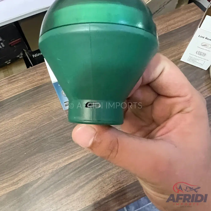 Green portable lint remover with a USB charging port.