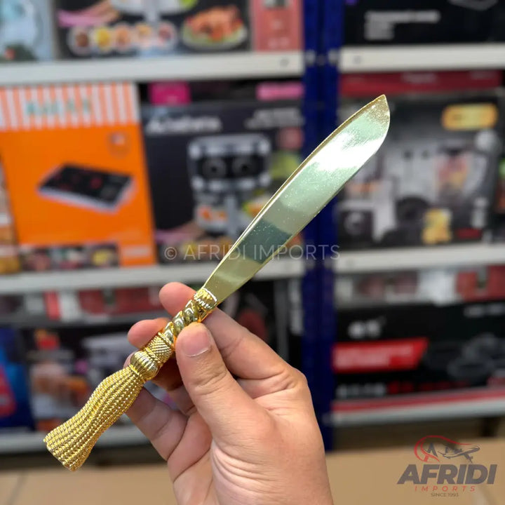A golden butter knife with an ornate, braided handle.