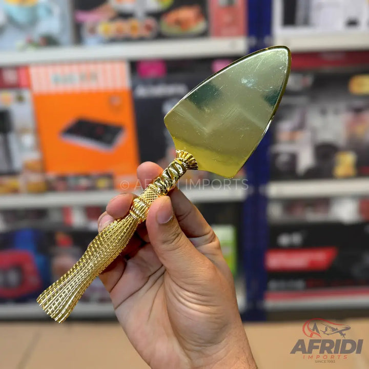 A gold-colored cake server with a decorative, textured handle.