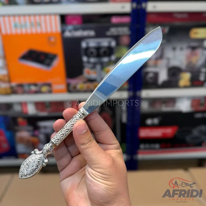 A silver-colored butter knife with an ornate, textured handle.