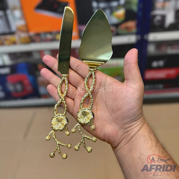 Gold-colored cake knife and server set with floral and branch-like handles.