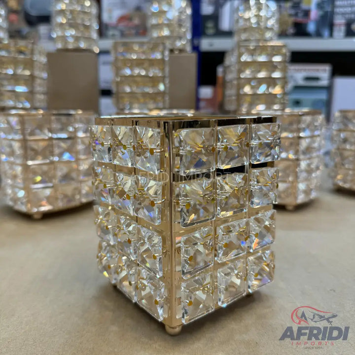 A shimmering, square-shaped crystal decorative container with a gold frame.