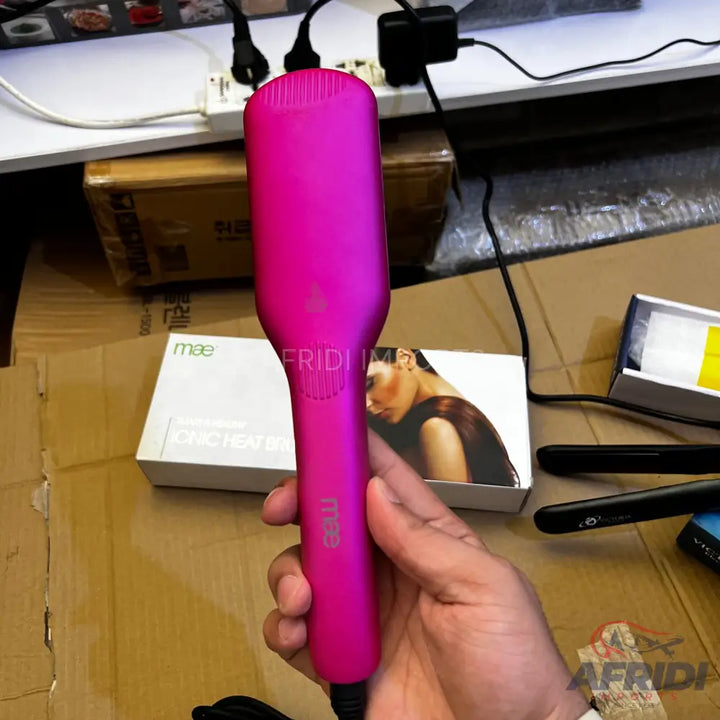 Pink electric hair straightening brush with a power cord.