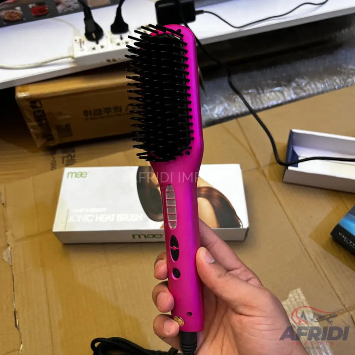 Pink hair straightening brush with black bristles and temperature controls.