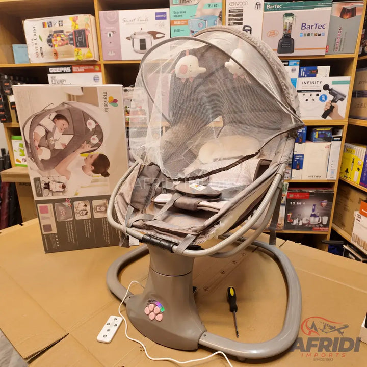 A grey baby swing with a mosquito net, overhead toys, and a remote control.