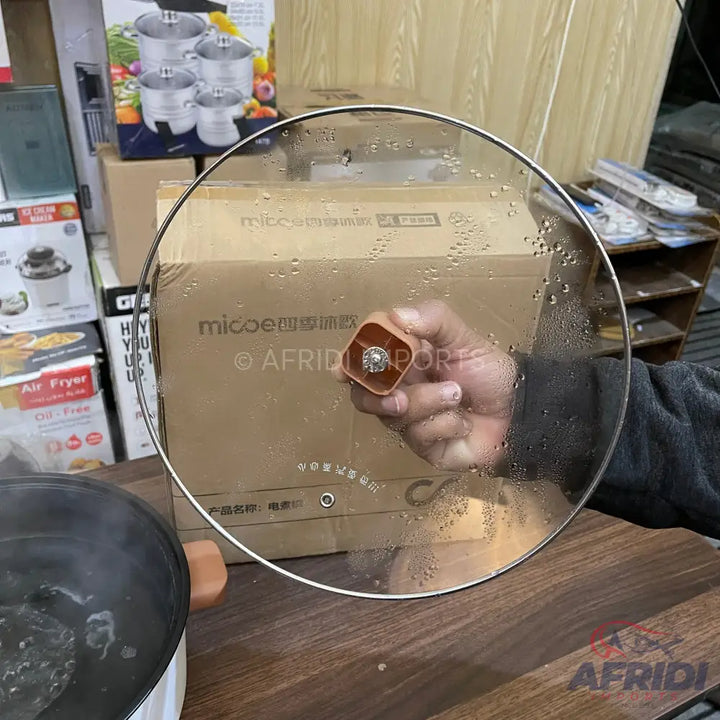A clear glass lid with a square, brown handle and silver rim.