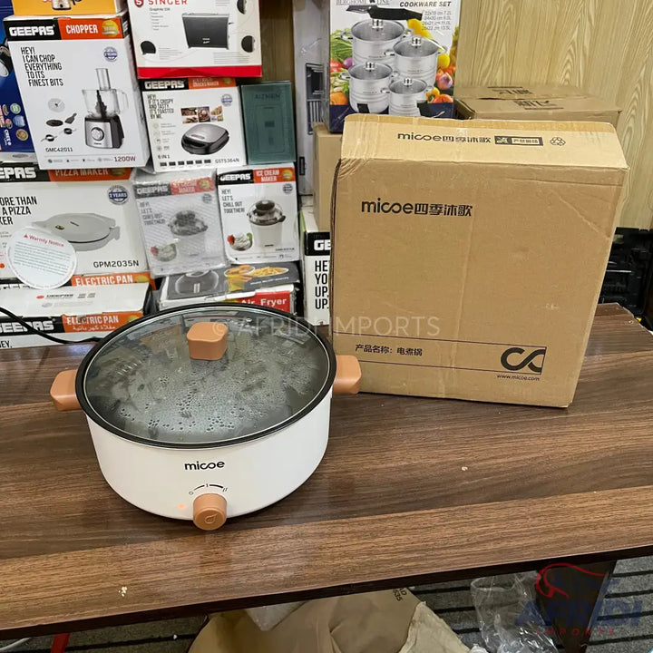 White electric hot pot with a glass lid and wooden accents.