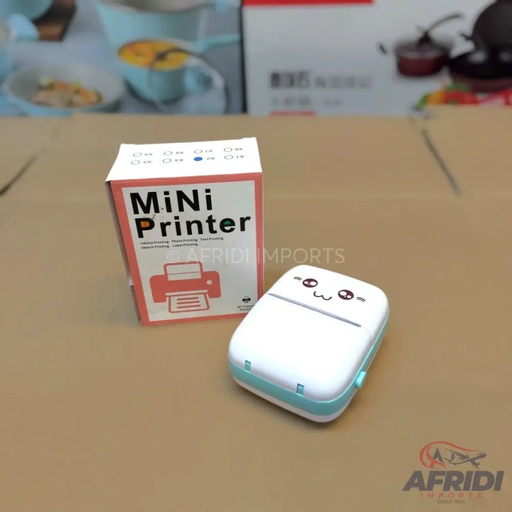 A white and light blue mini portable printer with a cute cartoon face design, next to its pink and white packaging box.