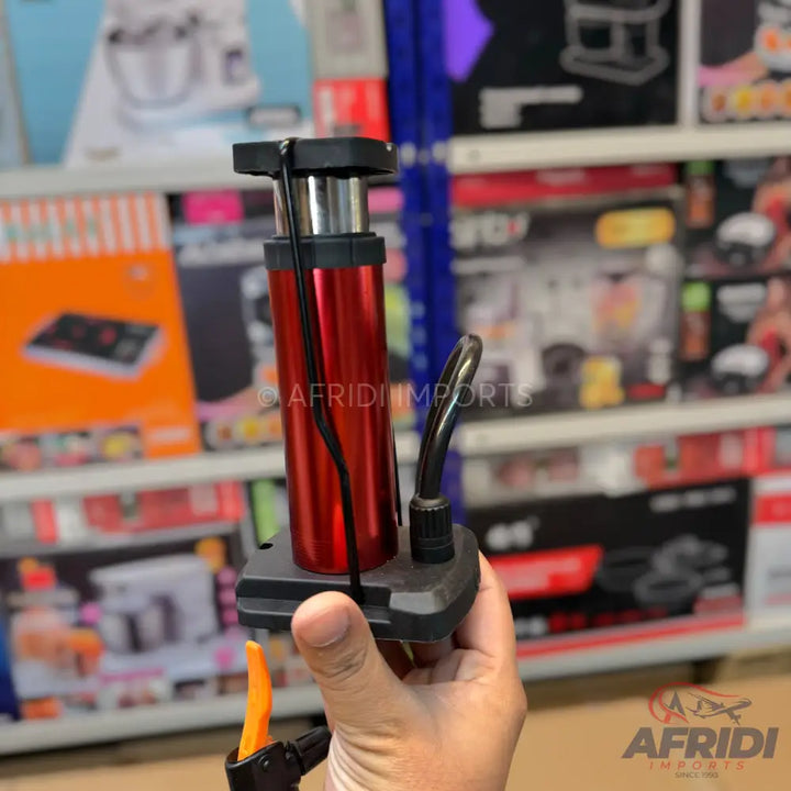 Red and black portable air pump with a flexible hose.