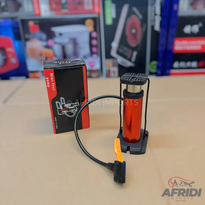 Red and black mini foot pump with a flexible hose and nozzle.