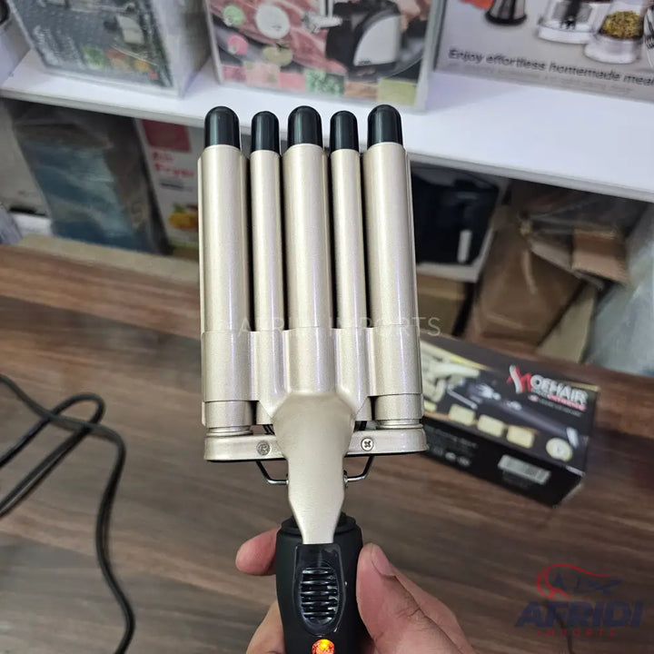 A five-barrel hair waver with a black handle and a golden heating element.