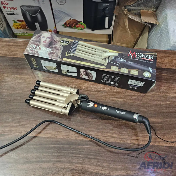 Gold-colored, four-barrel hair waver with a black handle and power cord.