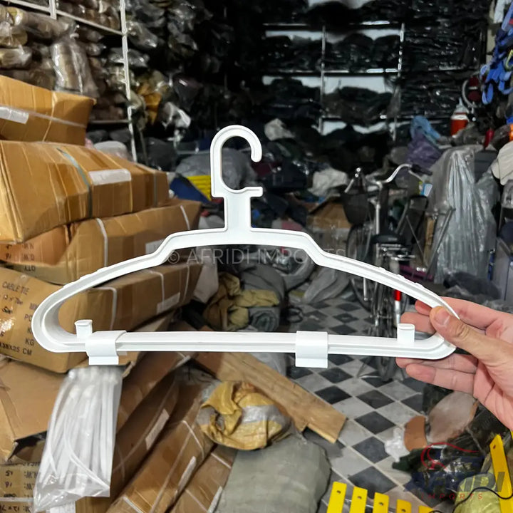 White plastic clothes hanger with an adjustable bottom bar.