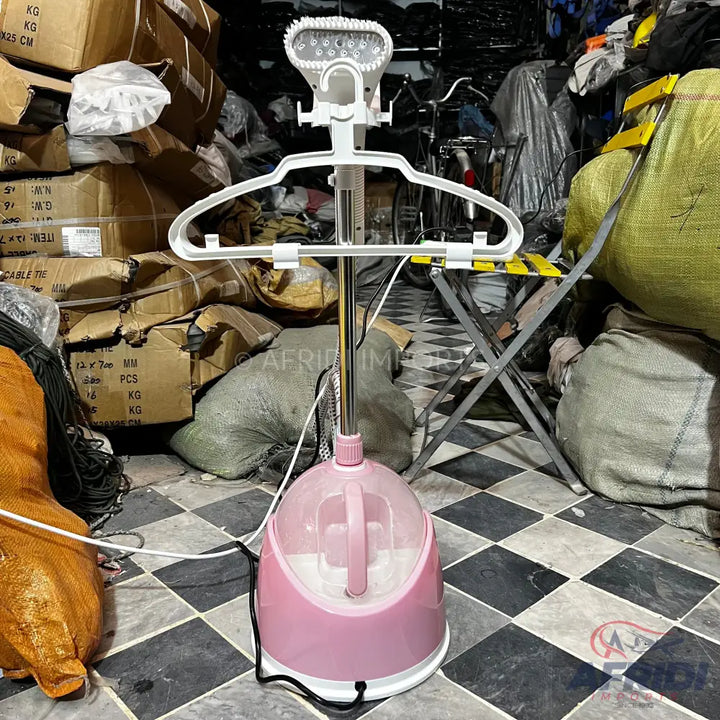 Pink and white upright garment steamer with a hanger and steam nozzle.