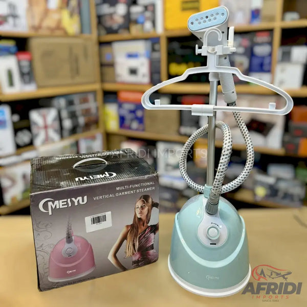A light blue vertical garment steamer with a white hanger attachment, a flexible hose, and a control dial, accompanied by its packaging box featuring a pink version of the steamer and a model.