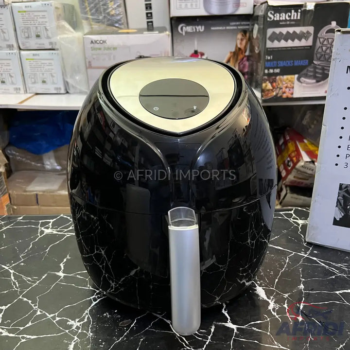 Black air fryer with a gold-toned top and a clear, cylindrical handle.