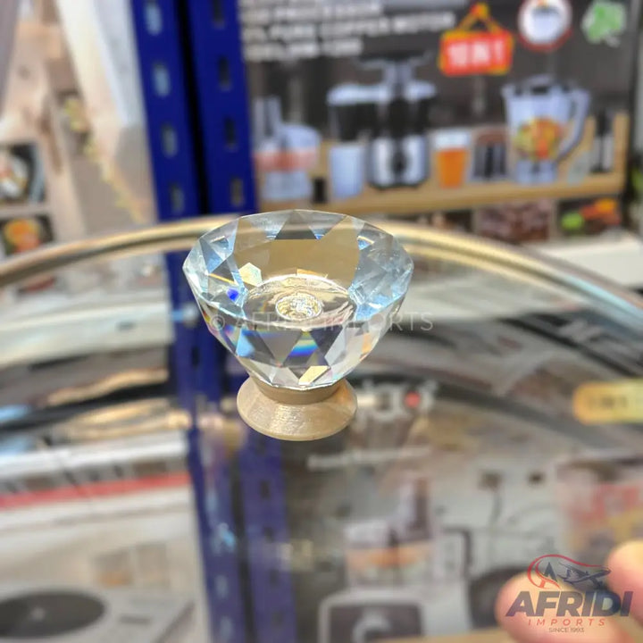 A faceted clear crystal knob with a gold-colored base.