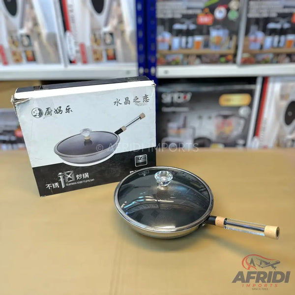 Stainless steel frying pan with a glass lid and a clear handle.