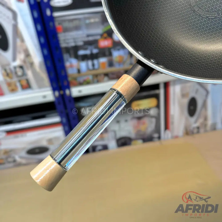Wok with a black non-stick surface and a clear glass handle with wooden ends.
