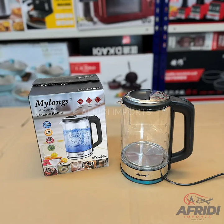A glass electric kettle with a black handle and a turquoise base, packaged in its box.